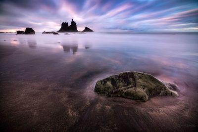 Rocks in sea against sky during sunset