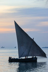 Sailboat sailing on sea against sky during sunset