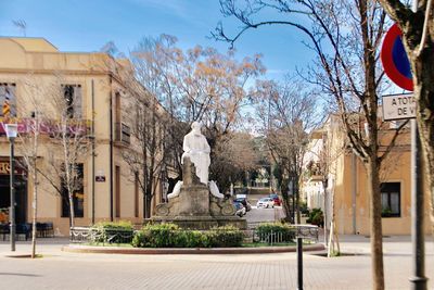 Statue amidst trees and buildings against sky