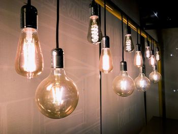 Illuminated light bulb hanging on wall