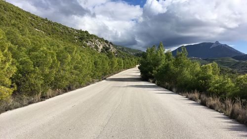 Road leading towards mountains against sky