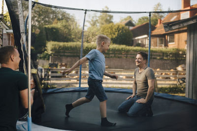 Smiling father and son playing in trampoline during weekend