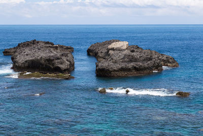 Rocks in sea against sky