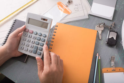Cropped hands of woman using calculator at desk