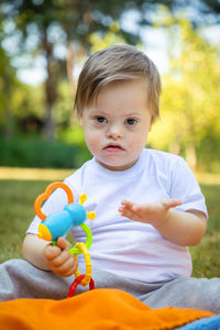 Portrait of cute boy holding toy while sitting outdoors