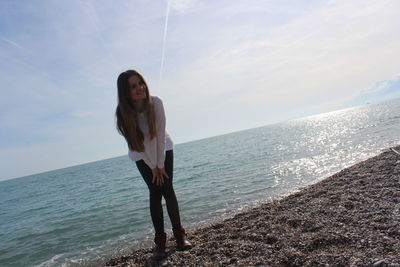 Woman standing on sea shore against sky