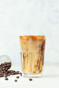 Iced coffee with milk in a tall glass with coffee beans. summer refreshment drink. 