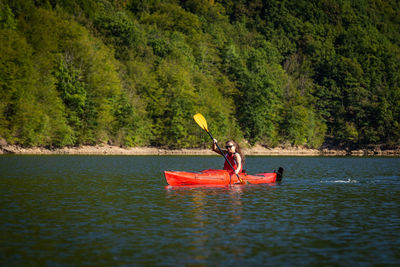 Man rowing boat in river against trees