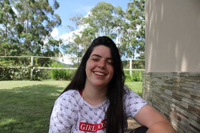 Portrait of young woman standing against trees