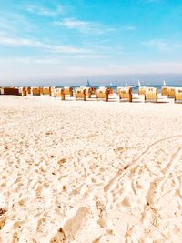 Hooded beach chairs on sand against sky