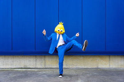 Full length of man standing against blue wall