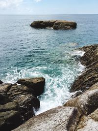 Rock formation in sea against sky