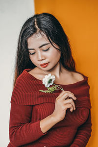 Beautiful young woman holding white flower