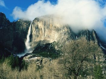 View of waterfall against cloudy sky