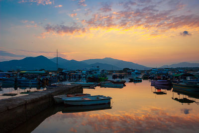 Boats moored at harbor against sky during sunset