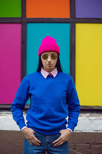 Fashionable brunette woman in a pink warm hat and sweater and sunglasses stands 