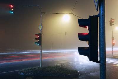 Light trail of cars passing crossroad at foggy night.