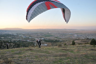 Rear view of person paragliding over landscape