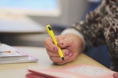 Midsection of woman holding pen on paper