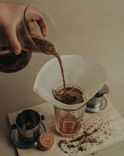 Midsection of person pouring coffee cup on table