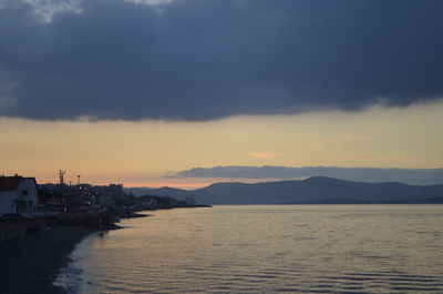 Scenic view of sea by buildings against sky during sunset