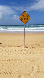 Information sign on beach against sky