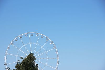 Low angle view of ferris wheel against clear blue sky