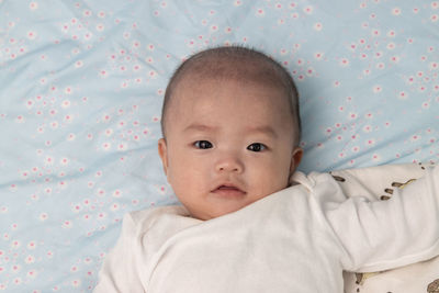 Portrait of cute baby lying on bed