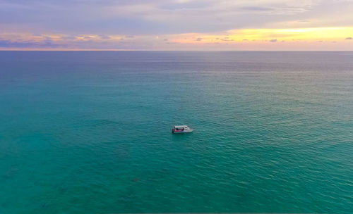 Boat sailing on sea against sky during sunset