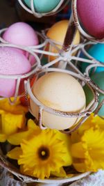 Close-up of colorful easter eggs in metallic stand above flowers