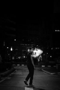 Side view of woman standing on street at night