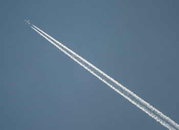 Low angle view of airplane forming vapor trial against clear sky