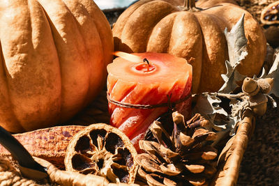 Cozy warm autumn composition with burning candle and pumpkins on knitted woolen plaid. 