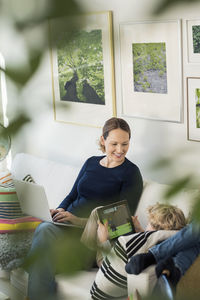 Happy mother looking at boy using digital tablet