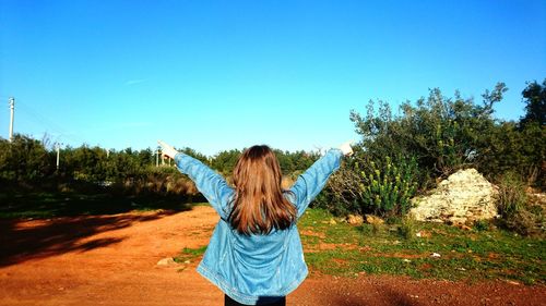Rear view of woman standing against blue sky