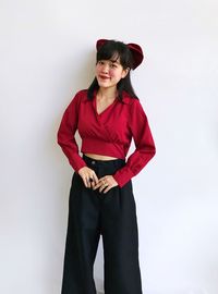 Portrait of young woman standing against white background