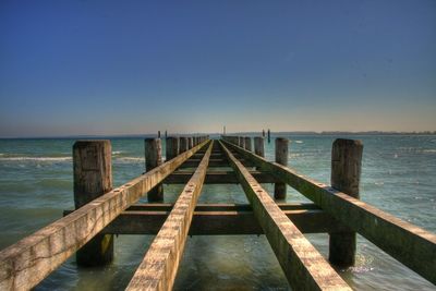 Wooden pier on sea against clear sky