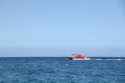 Boat sailing on sea against clear sky