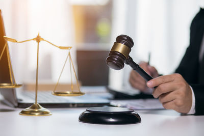 Close-up of hand holding clock on table