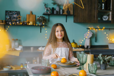 Cute baby girl is sitting at a festive table set for christmas and eating