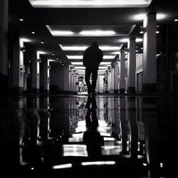 Rear view of man walking in illuminated building