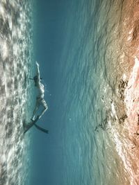 Underwater view of woman swimming in sea with diving fins