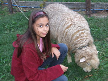 Portrait of young woman with sheep grazing on field