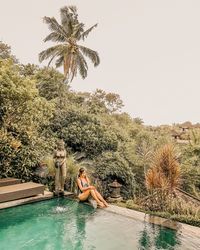 Man relaxing in swimming pool against sky