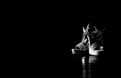 Close-up of shoes on table against black background