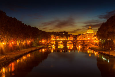 Illuminated bridge over river against sky at night