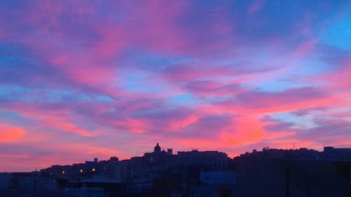 Buildings in city against dramatic sky