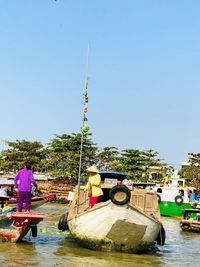 People in boat by river against clear sky