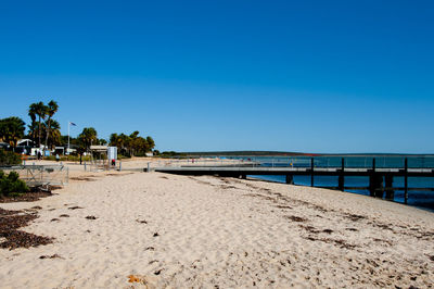 Surface level of beach against clear blue sky