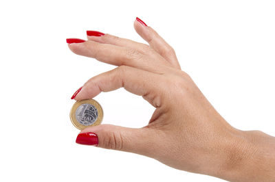 Close-up of hand holding ring against white background